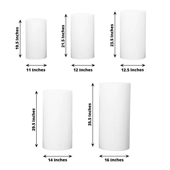 Various sizes of white cylindrical candles on a plain background