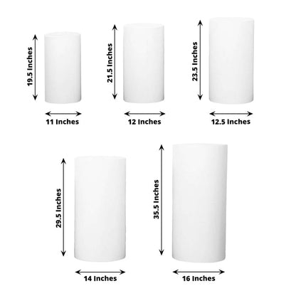 Various sizes of white cylindrical candles on a plain background