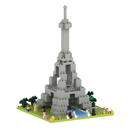 Build Parisian charm with Brixies’ Small Gift Box Large Eiffel Tower: a gray micro-brick model on a square base, accented by green, pink, and yellow trees and flowers plus a blue river in front.