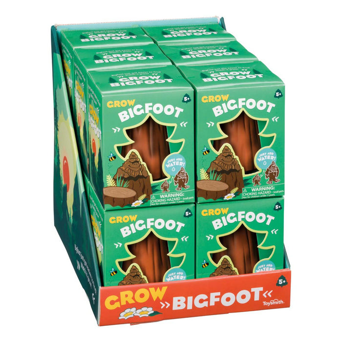 A Toysmith display box holds several green Toysmith Grow Bigfoot packages, each featuring a cartoon Bigfoot and stating the toy grows in water. The box’s bottom boldly reads "Grow Bigfoot.